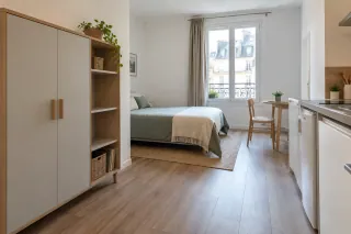Studio meublé avec armoire à étagères et passage dégagé