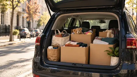 Cartons de dons chargés dans le coffre d'une voiture avant dépôt